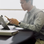  a man using a phone and laptop 