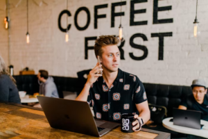 a man working on their laptop and speaking to their tax consultant in a cafe