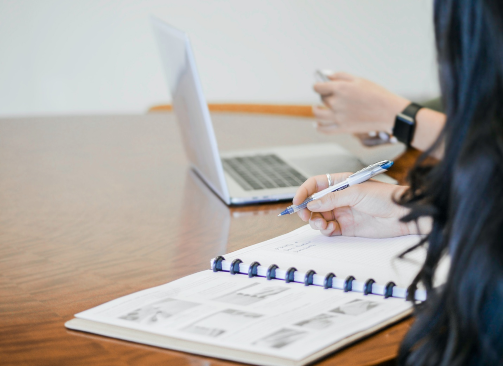 A person working on a register and a laptop