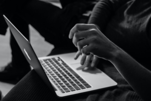 a grayscale photo of person using MacBook