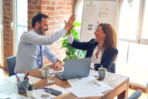 Two people celebrating with a high five in an office.