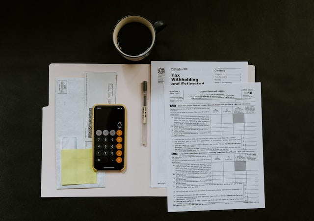 A phone, a pen, and some tax documents on a desk.