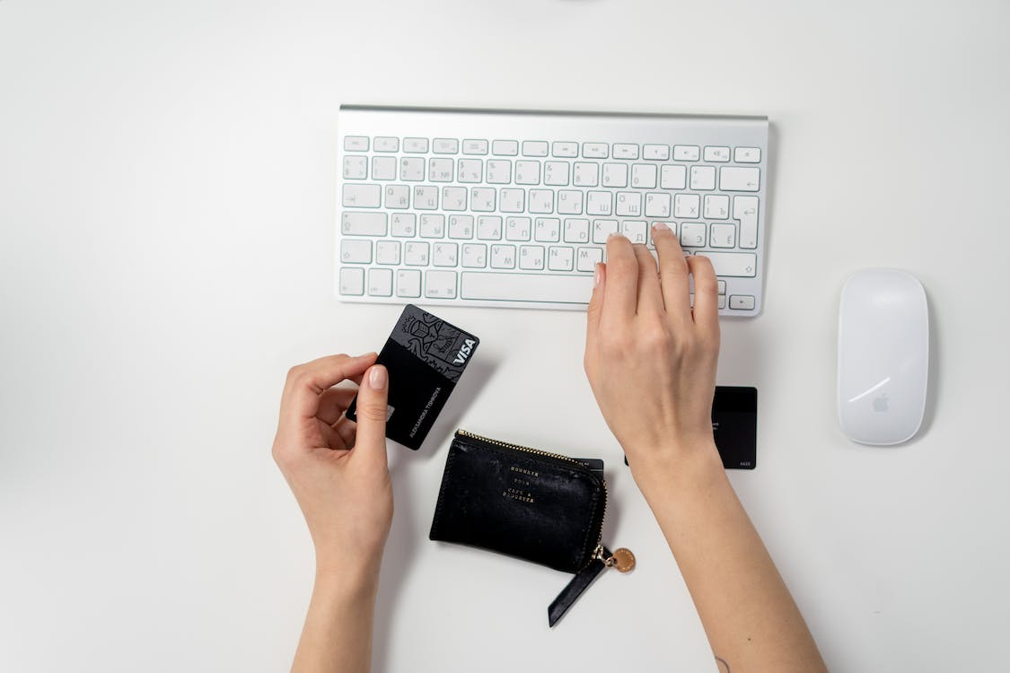 Person holding receipts and credit card while using a laptop