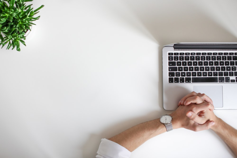 Person’s hands near a laptop on a white desk