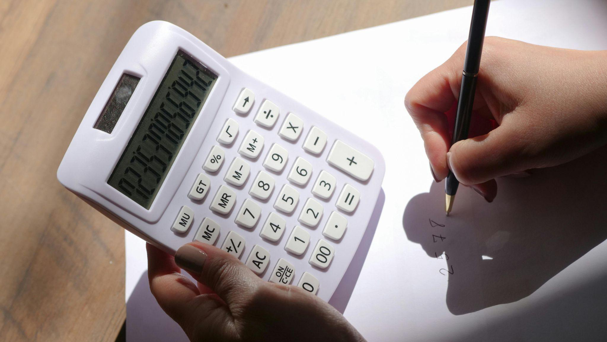A person using a calculator to calculate savings