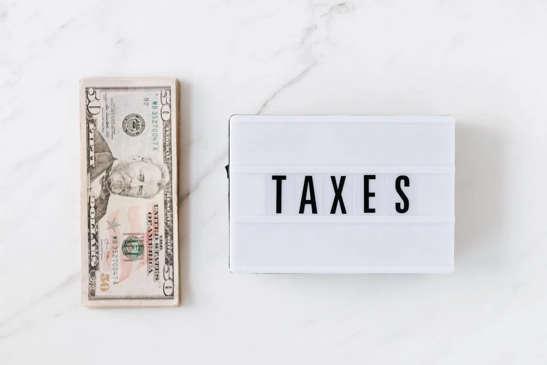 an American dollar bill next to a box that reads ‘taxes’