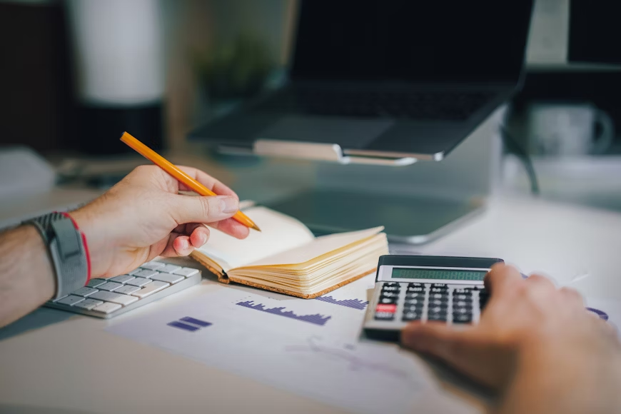 a person using a calculator and writing in their notebook
