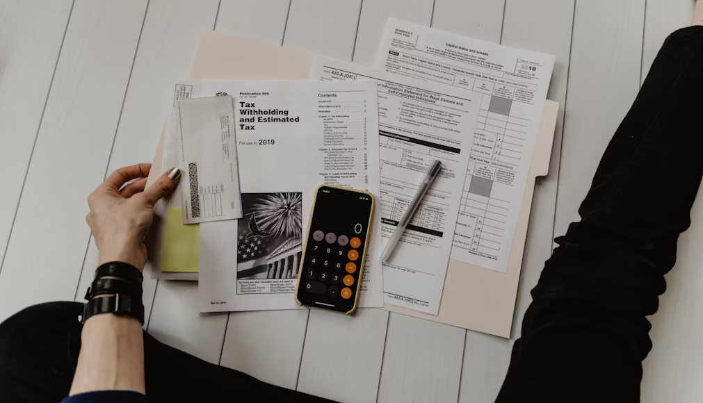 a person sitting with legs spread, going through a folder with tax papers