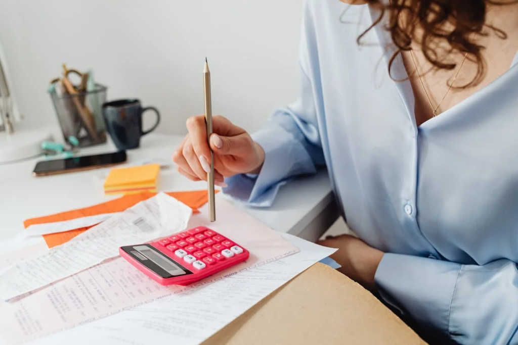 a woman wearing a blue button-down holding a pencil while calculating