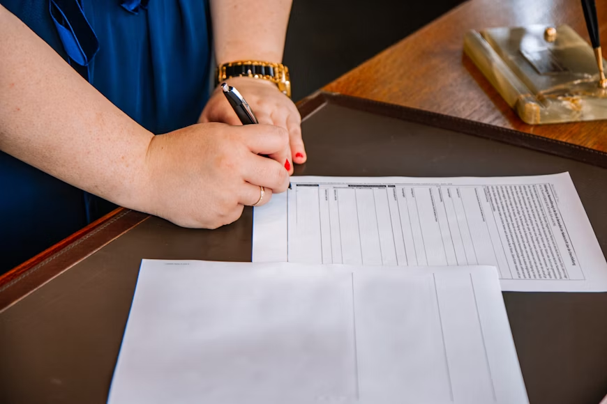 close-up of a woman going through tax papers and signing it