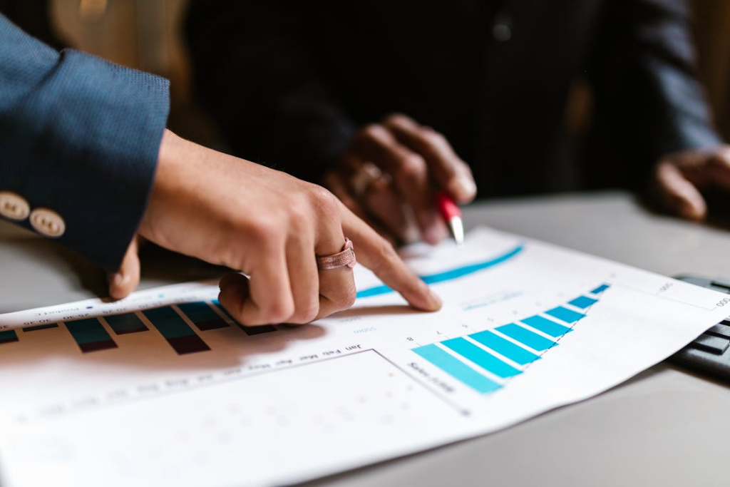 people point at a graph on a paper with a pen and finger
