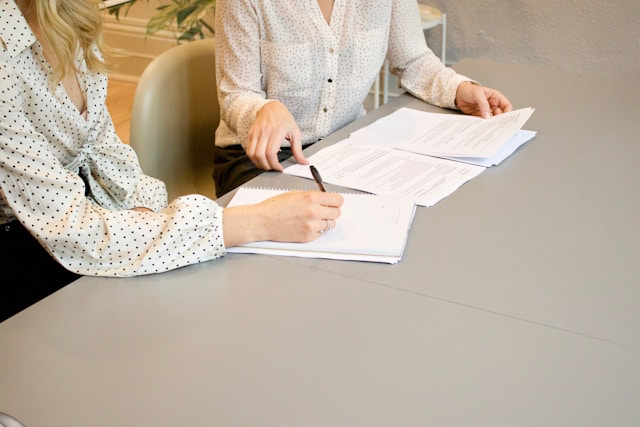 This photo shows two people discussing and writing on tax documents
