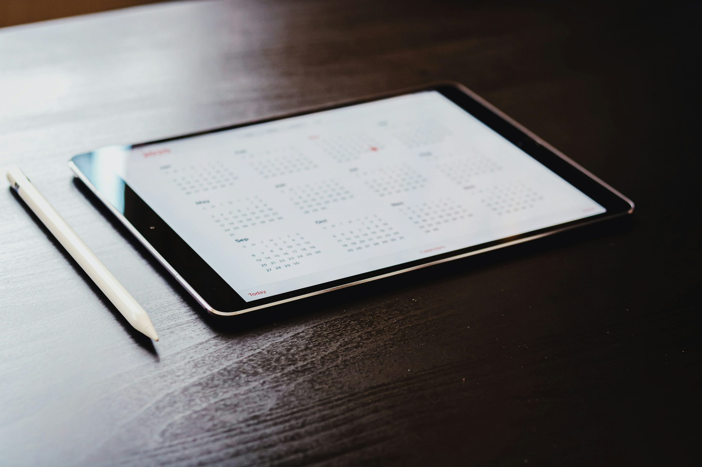 Tablet placed on a wooden table showing a calendar