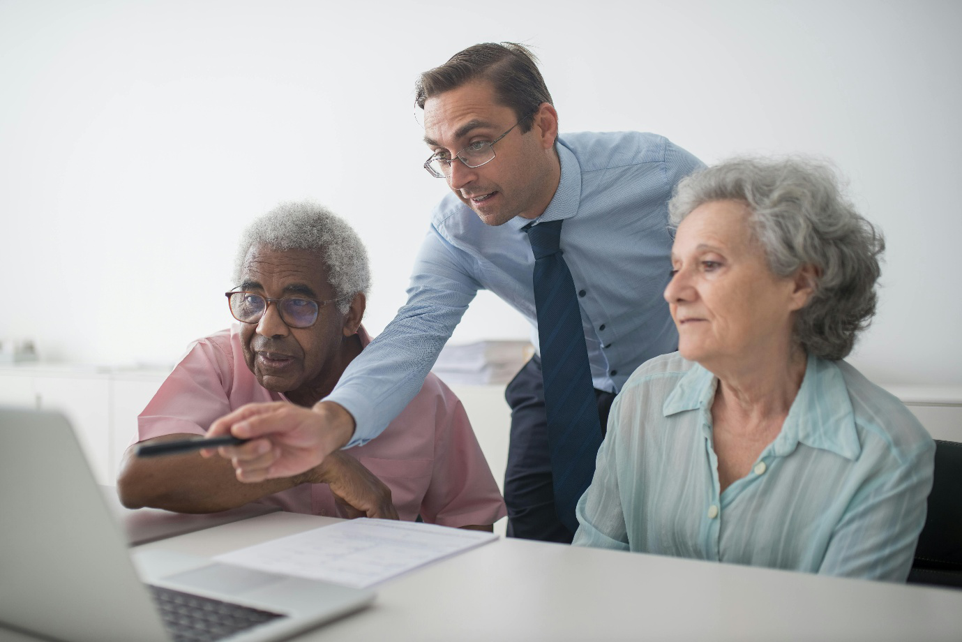 A photo showing a man pointing at the laptop screen for the elderly clients