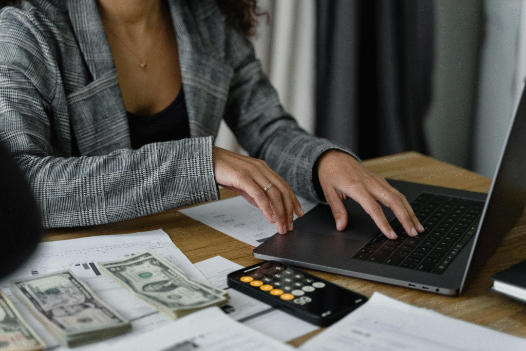 A photo showing a woman working on a laptop and a calculator