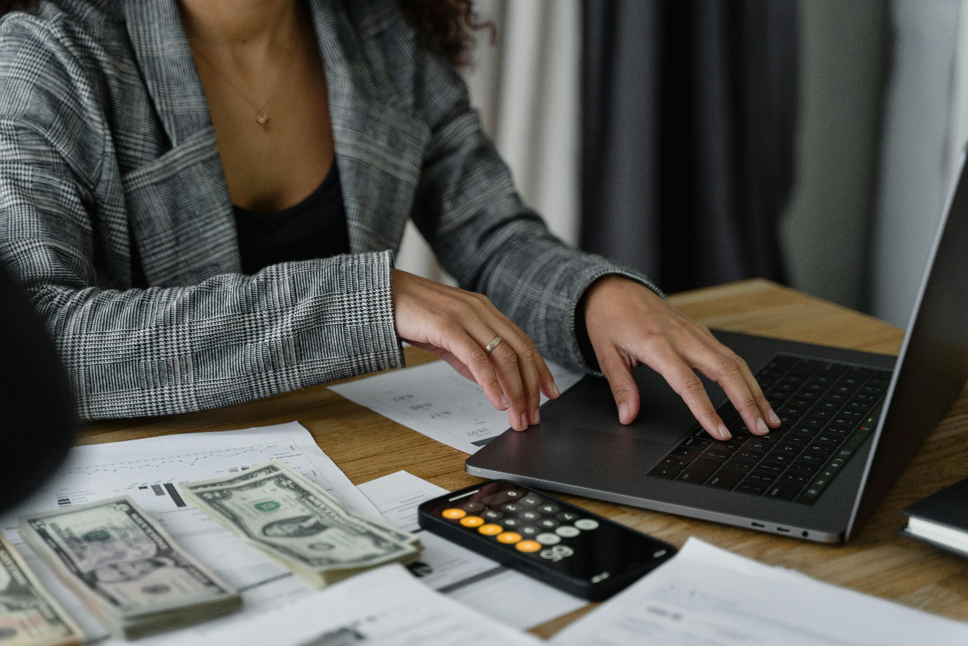 A photo showing a woman working on a laptop and a calculator