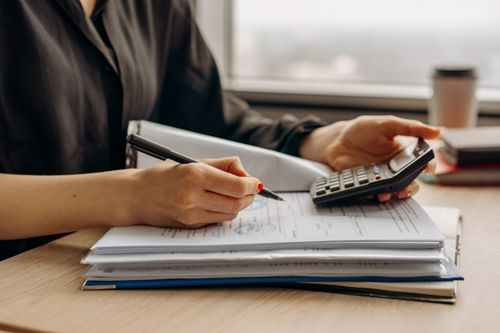 Business professional calculating operating costs while reviewing financial documents