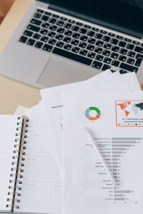 Laptop, notebook, and printed financial reports arranged on an office desk