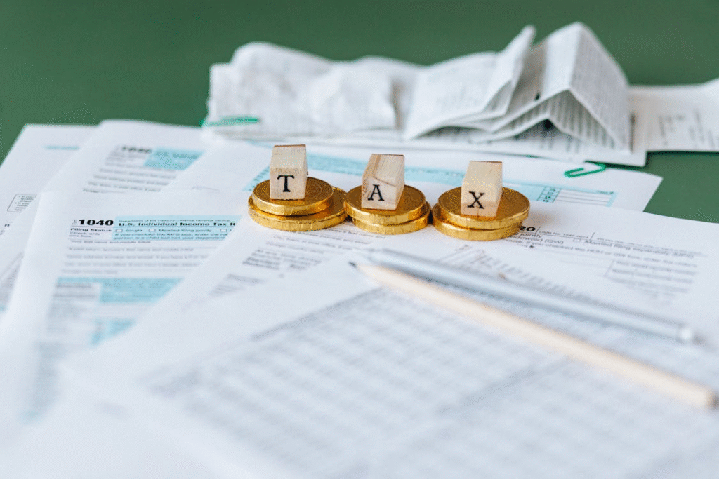 Tax documents, coins, and Tax written on wooden blocks placed on a green surface